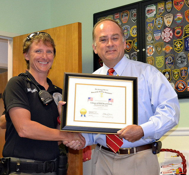 President Bill Price presents a flag certificate to Caroline Mitchell, Director of Public Safety